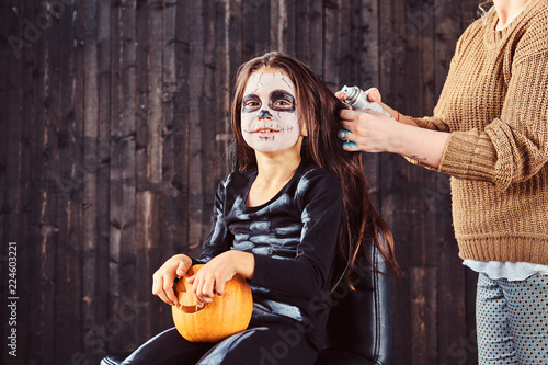 Mom makes hair styling with a hairspray for Halloween party. Halloween concept. photo