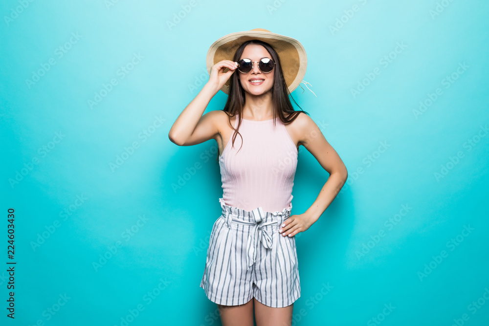 Portrait of pretty woman in sunglasses and hat over blue colorful background. Summer vocation.