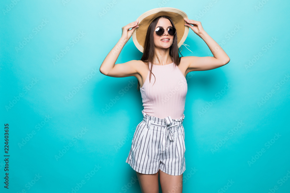 Portrait of pretty woman in sunglasses and hat over blue colorful background. Summer vocation. Portrait of pretty woman in sunglasses and hat over blue colorful background. Summer vocation.