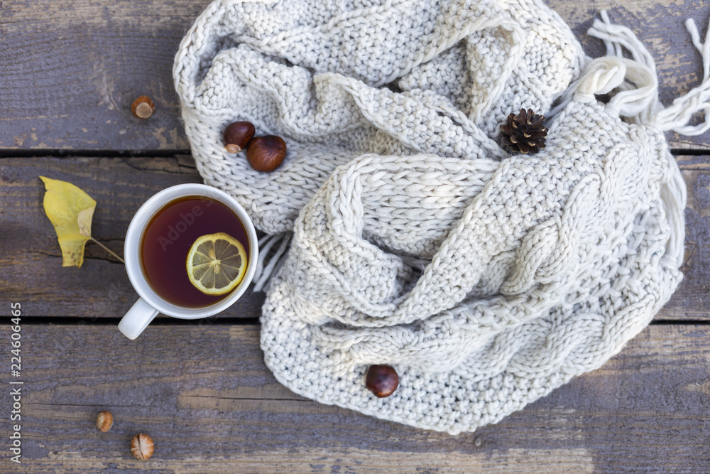 tea in tea cup with lemon, knitted scarf near at wood background