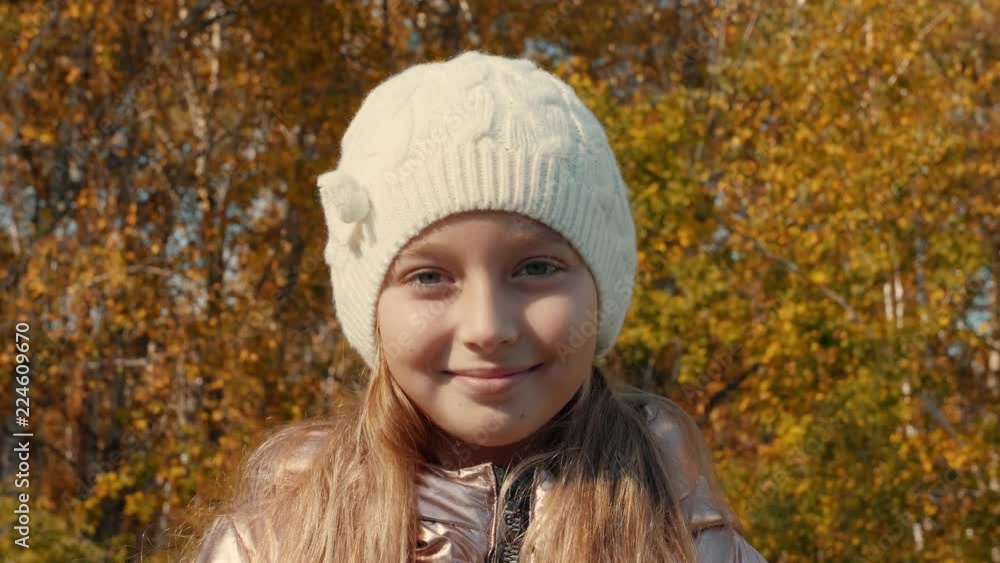 Portrait teenager girl in cap on yellow foliage of autumn trees close up Portrait teenager girl in cap on yellow foliage of autumn trees close up