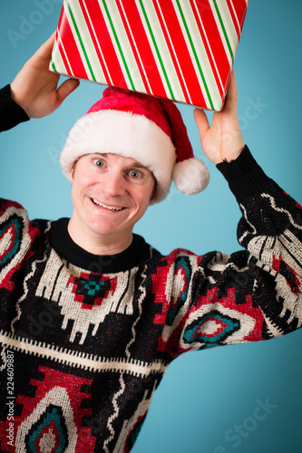 Canvas Print Happy Christmas Guy in Ugly Sweater and Santa Hat with Gift