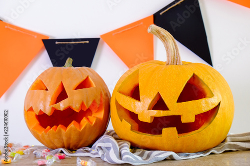 Tableau sur toile Few orange pumpkins of different size carved into Jack o Lantern on wooden table