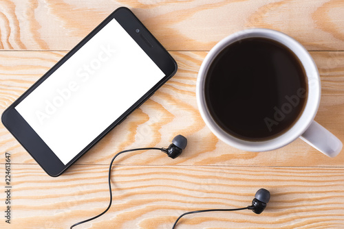 coffee, telephone and headphones on a light wooden background