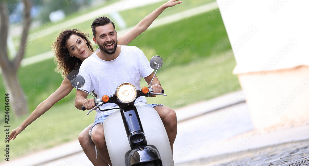 Obraz premium Young couple riding motor scooter in city