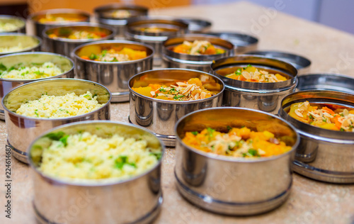 Rows of Tiffin (Dabba) Meal Box Containers Filled with Herbed Couscous and Vegetable Stew