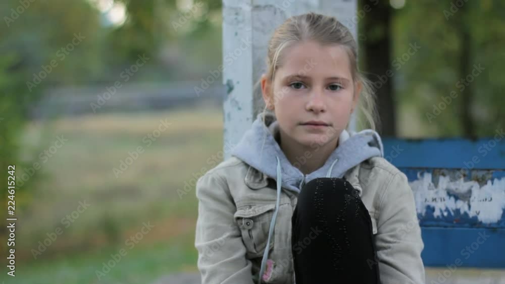 Pretty preteen girl child calm looking at camera sitting alone outdoors Stock ビデオ | Adobe Stock 