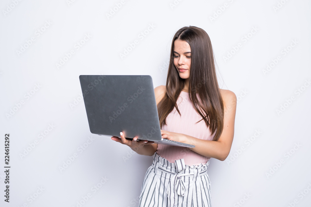 Portrait of happy woman standing with laptop isolated on gray background Portrait of happy woman standing with laptop isolated on gray background