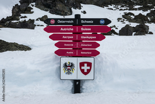 Sign post showing two directions for two ski resorts in European Alps - Ischgl and Samnaun. Austria and Switzerland written in multiple languages