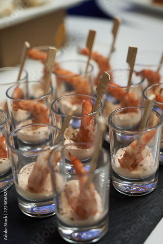 Shrimp cocktail with sauce on black stone tray table. Glasses with seafood snacks  close-up. Smorgasbord  food concept 