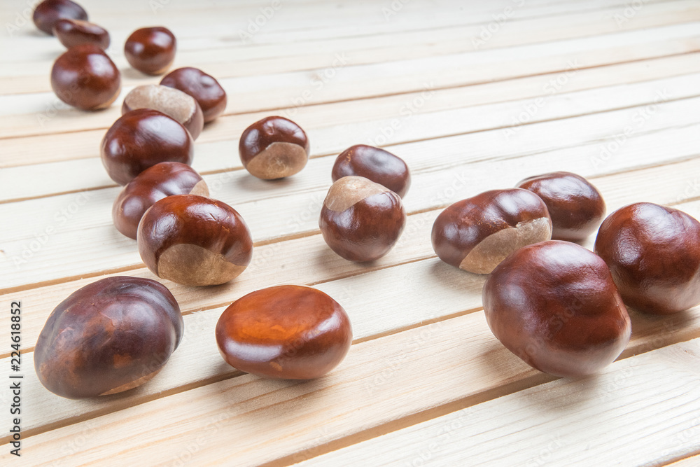Fresh chestnut fruit scattered on light wood table Fresh chestnut fruit scattered on light wood table