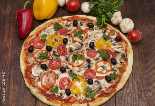 Pizza with ham, pepper and olives. Delicious italian pizzas on a wooden background