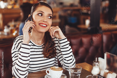 Beautiful young woman talking on the phone at coffee shop