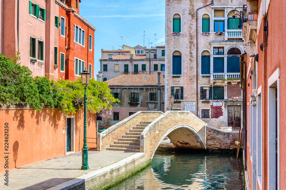 Venice, Italy: scenic canal with a bridge, colorful buildings and flowers