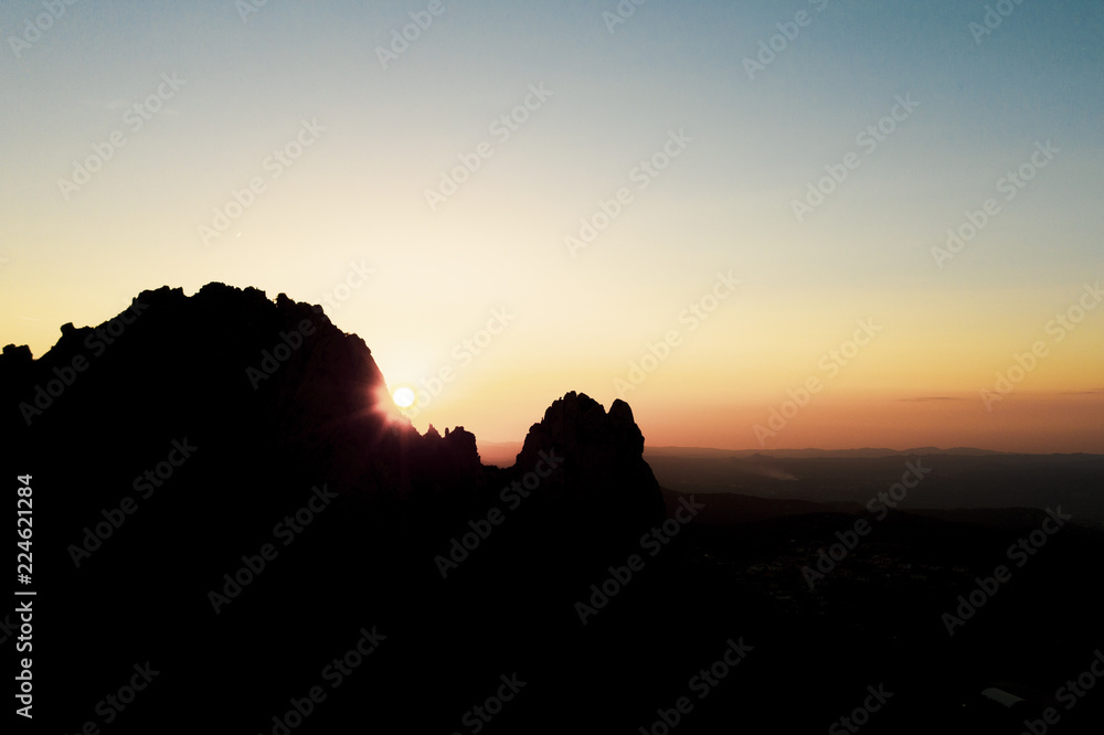 Aerial view of a spectacular sunset behind some rocky mountains in Sardinia, Italy.