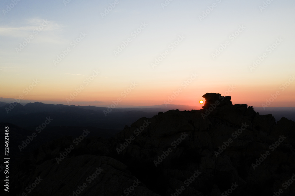 Obraz premium Aerial view of a spectacular sunset behind some rocky mountains in Sardinia, Italy.