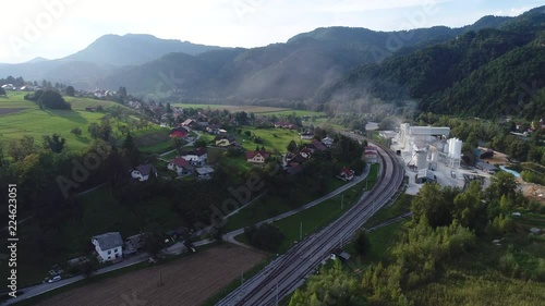 4k aerial shot of a small rural town on a hill with a factory and a passing train photo