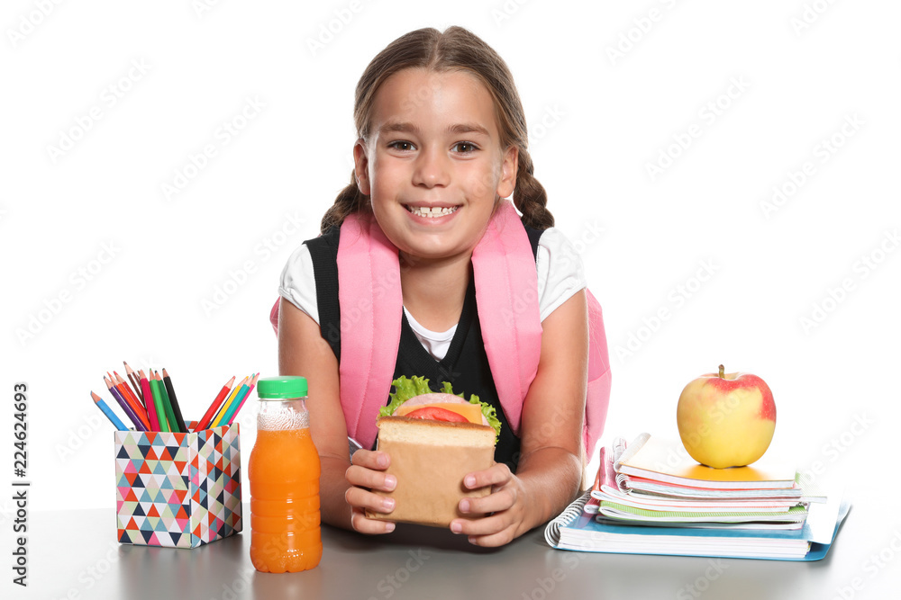 Schoolgirl with healthy food and backpack sitting at table on white background Schoolgirl with healthy food and backpack sitting at table on white background