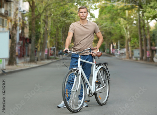 Handsome man with bicycle outdoors on summer day