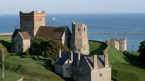 igh angle view of historic Dover Church and ancient Roman lighthouse as a far-distant ferry leaves the harbor at Dover bound for for France. photo