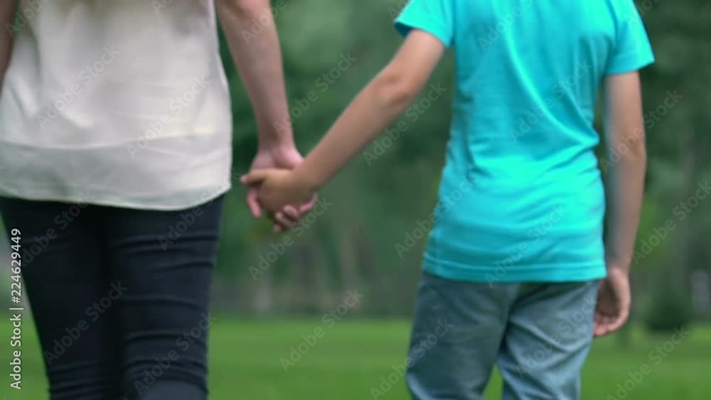 Adopted child and foster mother holding hands, going together in bright future