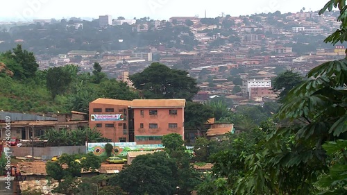 Wide view of Yaounde from a hill with a tree in the foreground, Cameroon. Heavy grey sky. photo