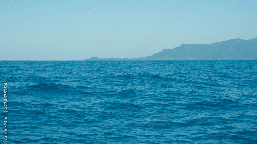 a deep blue sea with island in distance with medium water wave ripple