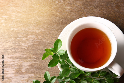 Herbal tea in hot white glass With leaves on its side And put on the wooden floor.