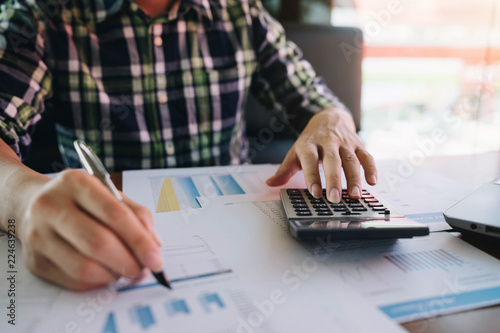 Businessman or accountant hand holding pen working with calculator and laptop computer.Business financial and accounting concept.