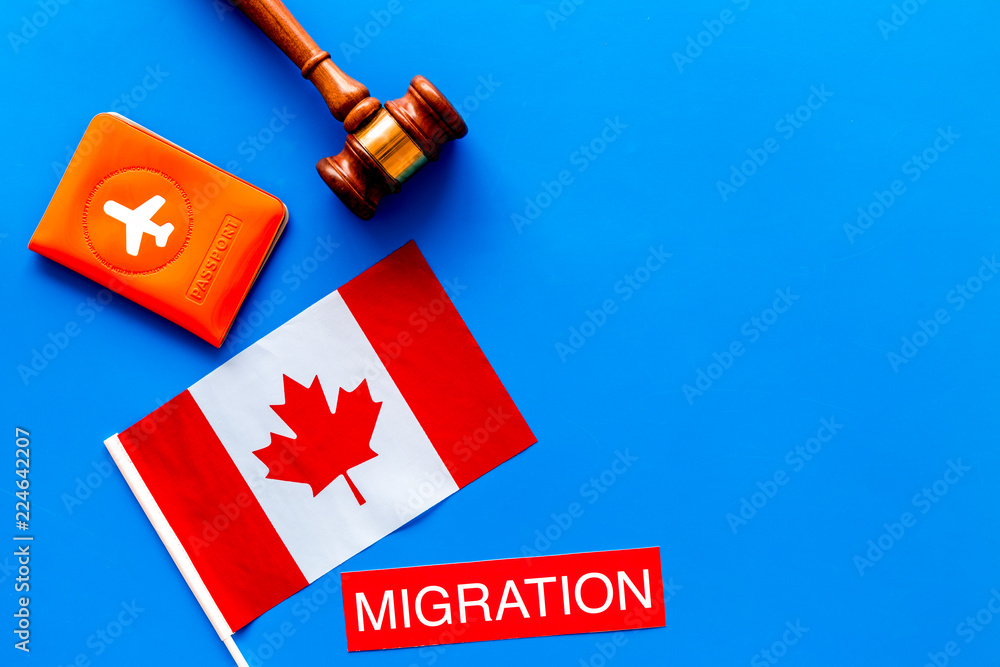 Immigration to Canada concept. Text immigration near passport cover and canadian flag, hammer on blue background top view space for text