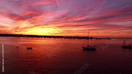 Aerial footage flying past anchored sailboats in the ocean into a colorful and fiery rich sunset background photo