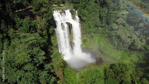 4k cinematic revealing pan of the powerful Tad Yuang waterfall in the Bolaven plateau in Laos, Southeast Asia with a small gazebo-style structure in the foreground. photo