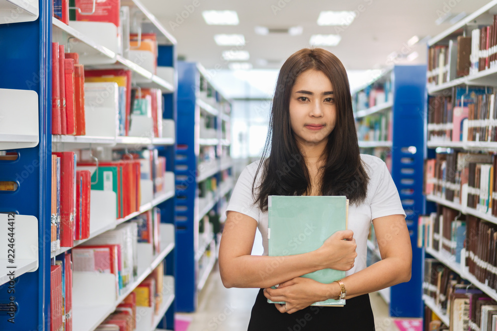 Portrait of young asian female college with book standing in library. Portrait of young asian female college with book standing in library.