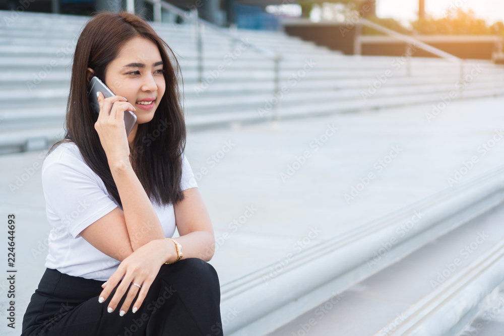 Young asian business woman in casual calling someone on phone and looking away.