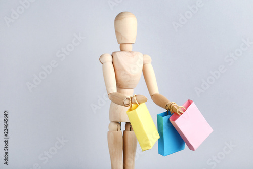 Small paper shopping bags with wooden figure on grey background