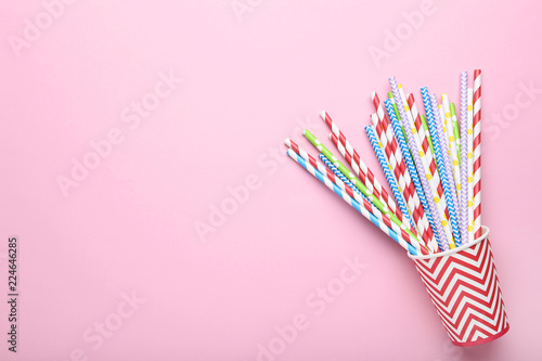 Red paper cup with colorful straws on pink background