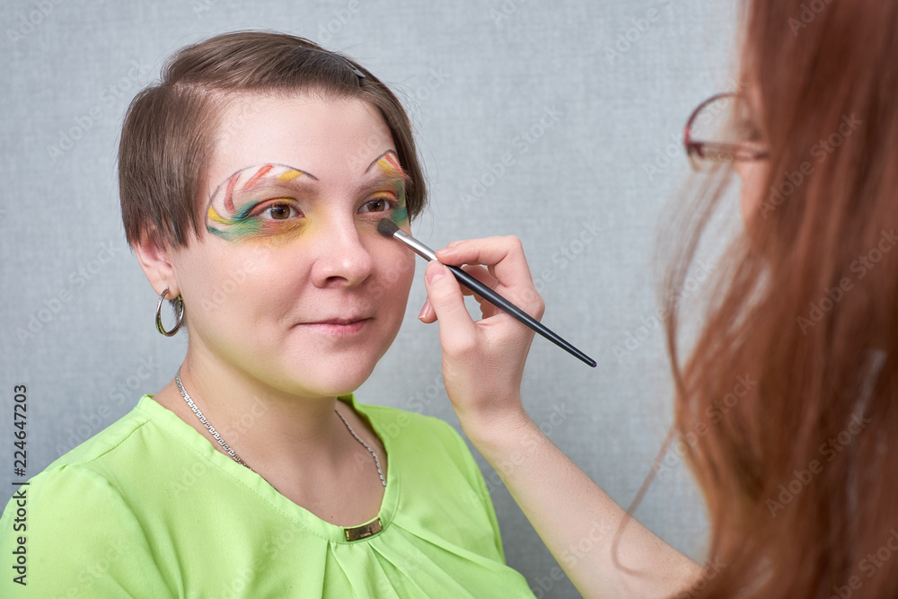 Professional visage artist applying artistic make-up , behind the scenes on set Professional visage artist applying artistic make-up , behind the scenes on set