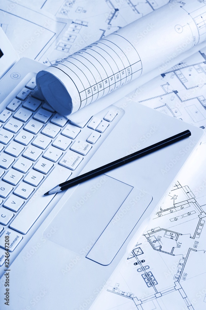 Blueprints with a drafting pencil and laptop on top of them Blueprints with a drafting pencil and laptop on top of them