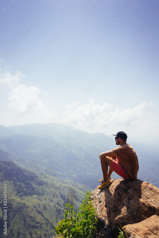 Travel concept. Man sitting on Ella Rocka enjoying mountain landscape, Sri Lanka