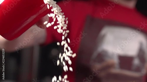 Slow motion shot of young Caucasian male chef pouring rice photo