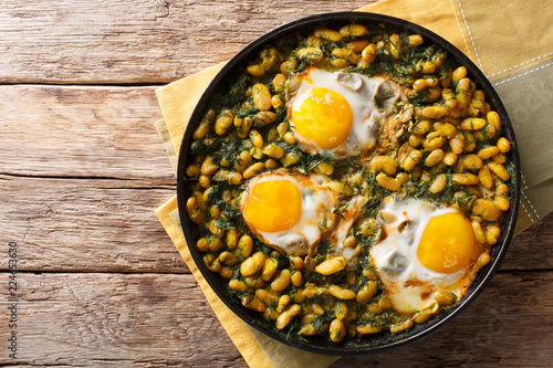 Tasty Iranian dish stew of beans and dill with fried eggs, garlic, turmeric close-up on a table. horizontal top view photo