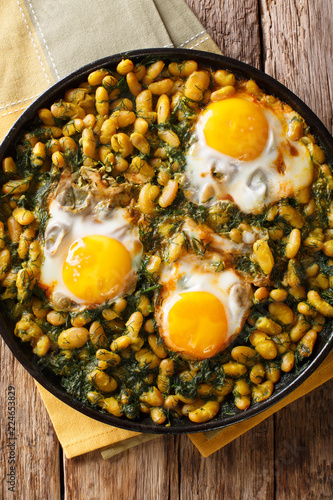 Iranian food Baghali Ghatogh stew of beans and dill with fried eggs close-up in a frying pan. Vertical top view photo