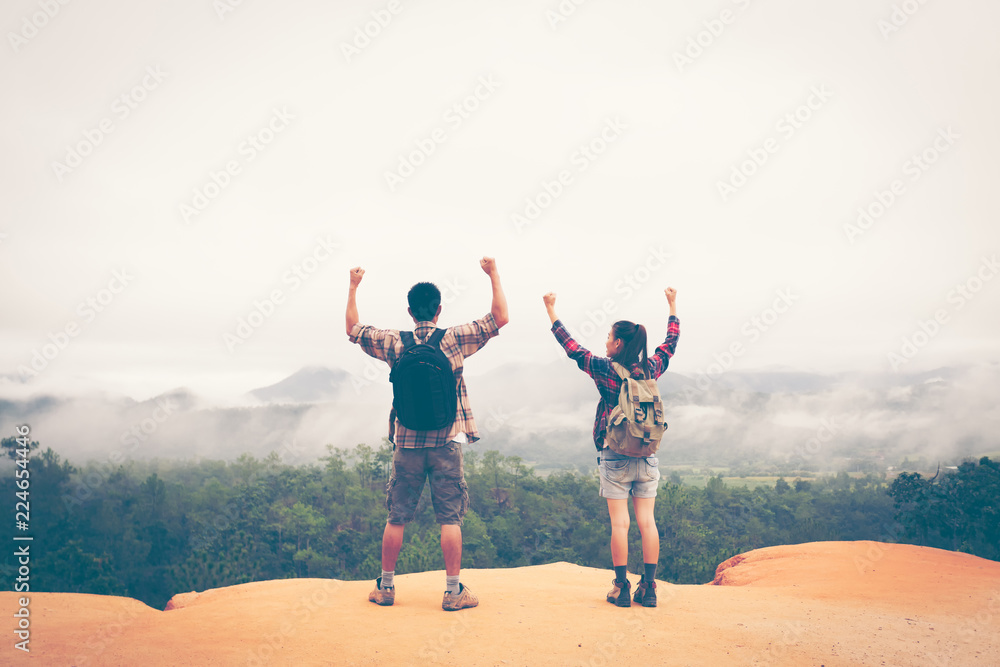 Two hikers relaxing on top of the mountain and enjoying sunset valley view Two hikers relaxing on top of the mountain and enjoying sunset valley view
