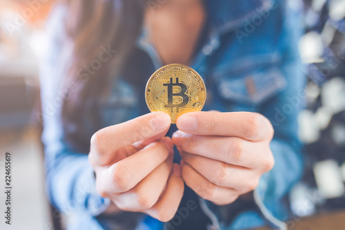 The hand of a woman holding a currency, bitcoin.