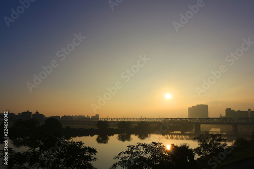 Scenery with sun behind the iron bridge across the river