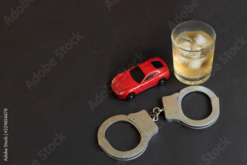 Fotografie Alcohol, handcuffs and car toy on color background