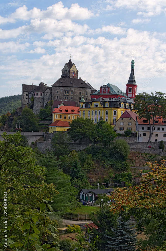 Scenic landscape view of medieval Loket Castle with colorful buildings by summer sunny day. Bohemia, Sokolov, Karlovarsky Region, Czech Republic Scenic landscape view of medieval Loket Castle with colorful buildings by summer sunny day. Bohemia, Sokolov, Karlovarsky Region, Czech Republic