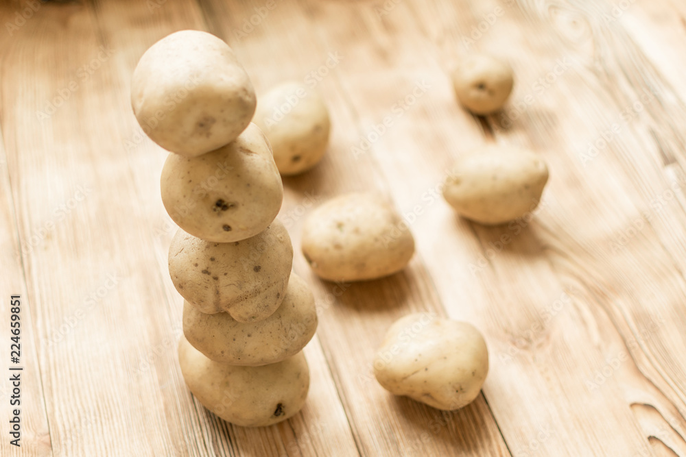 Raw tubers of potatoes in the form of a pyramid on a wooden background. Raw tubers of potatoes in the form of a pyramid on a wooden background.