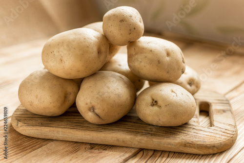 Raw potato tubers on a wooden background.