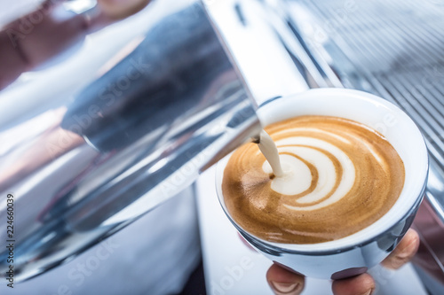 Barista making art coffee and pouring milk in to cup